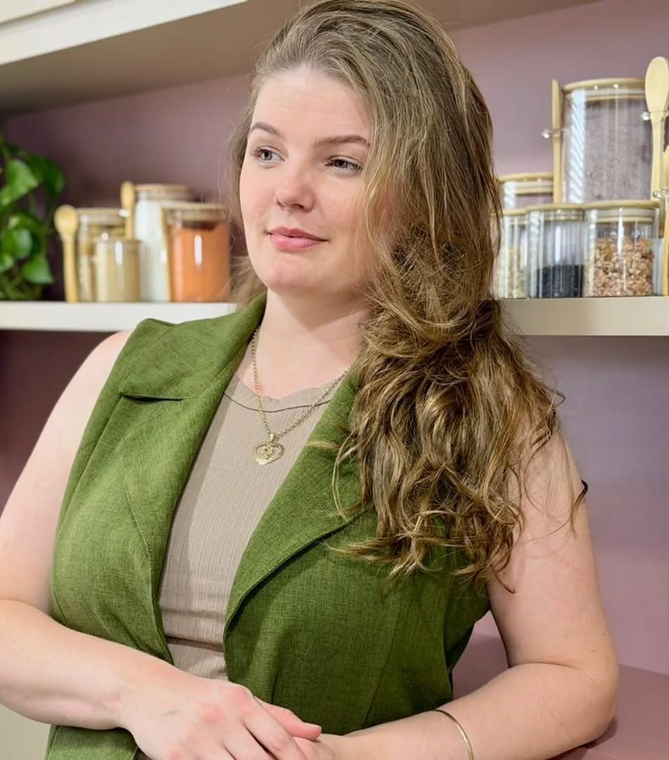 Fernanda Schneider no seu espaço de estética natural, com prateleiras de ingredientes ao fundo